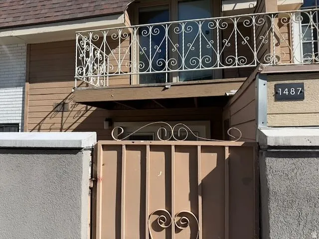 Entry gate featuring decorative scrollwork and a stucco-finished pillar