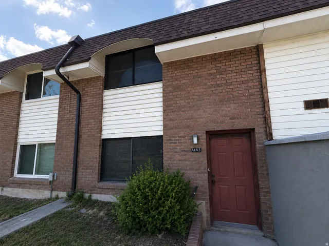 Brick and siding exterior featuring a red entry door with adjacent wall-mounted lighting