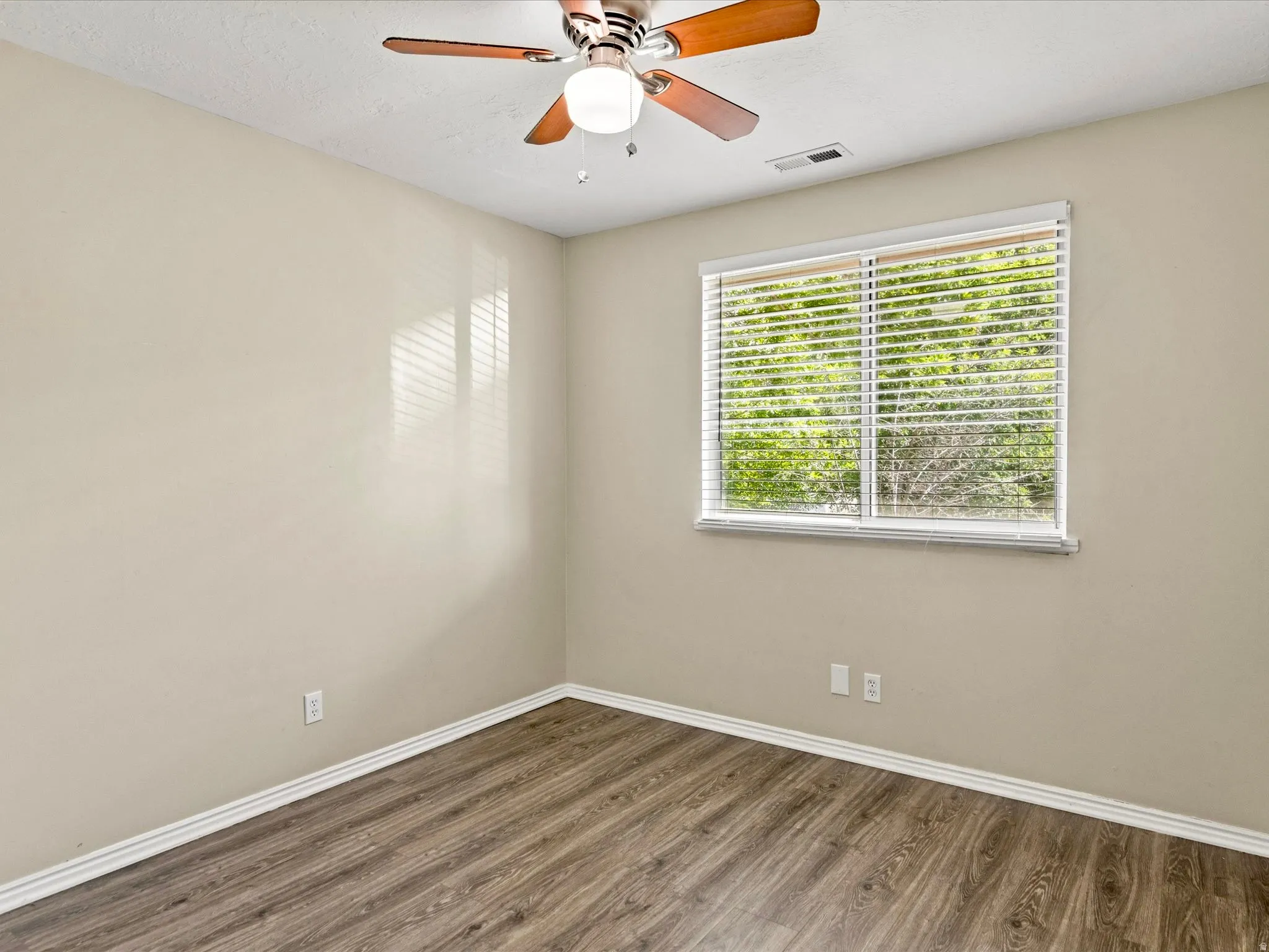 Room with wood-finish flooring, neutral-toned walls, and white baseboards