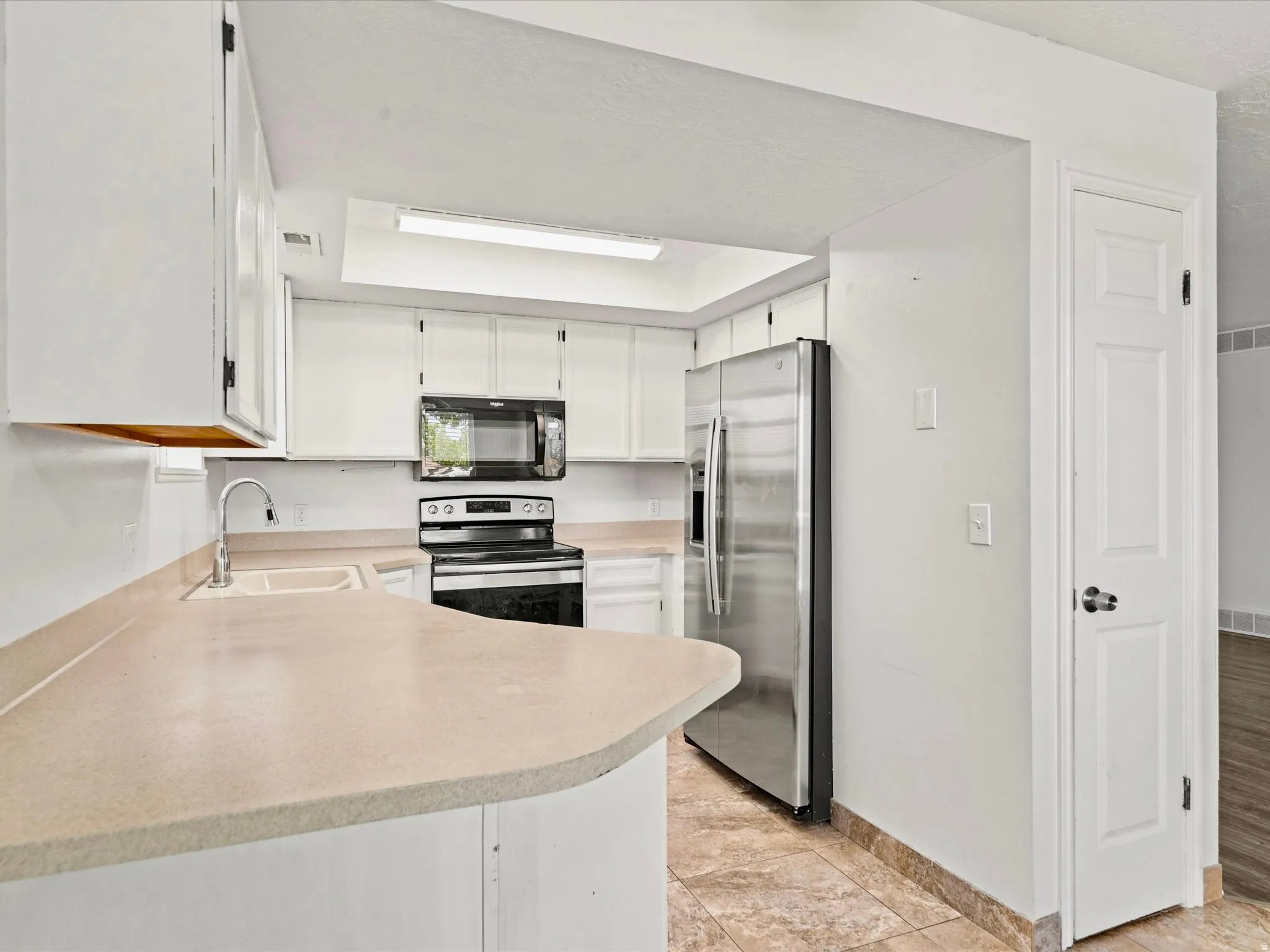 Kitchen featuring white cabinetry, light-toned countertops, and stainless steel appliances