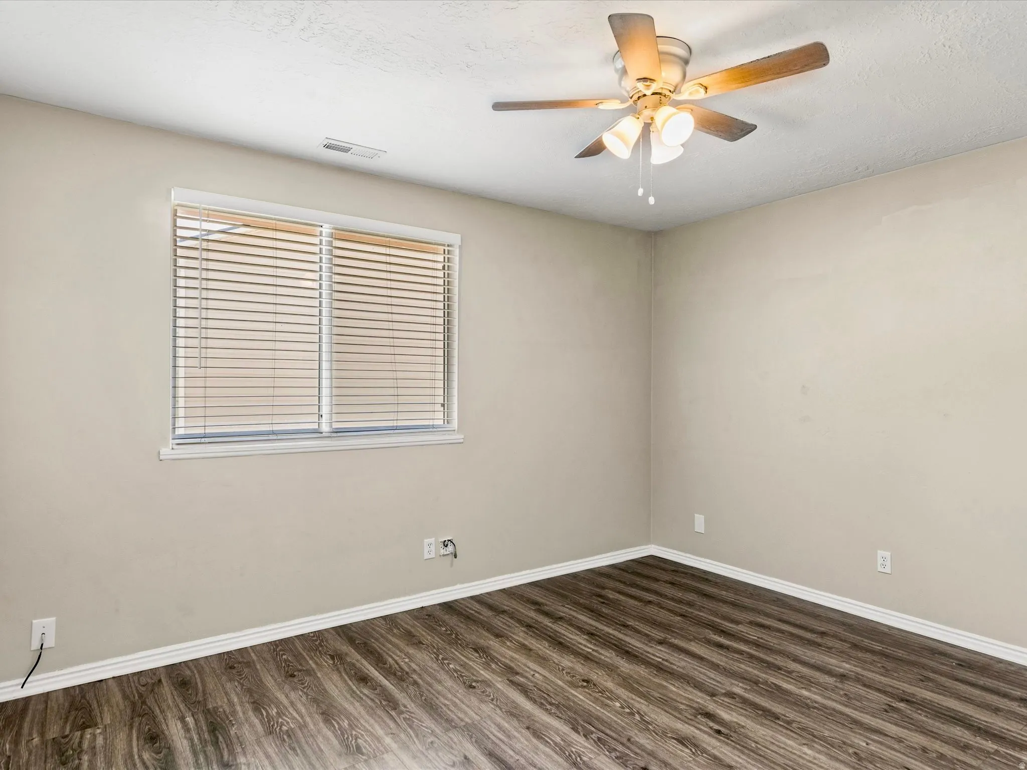 Room featuring wood-finish flooring, neutral wall tones, and white baseboards