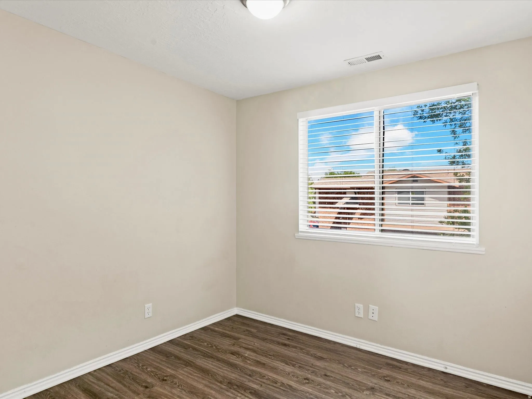 Room featuring wood-finish flooring, light-toned walls, and white baseboards