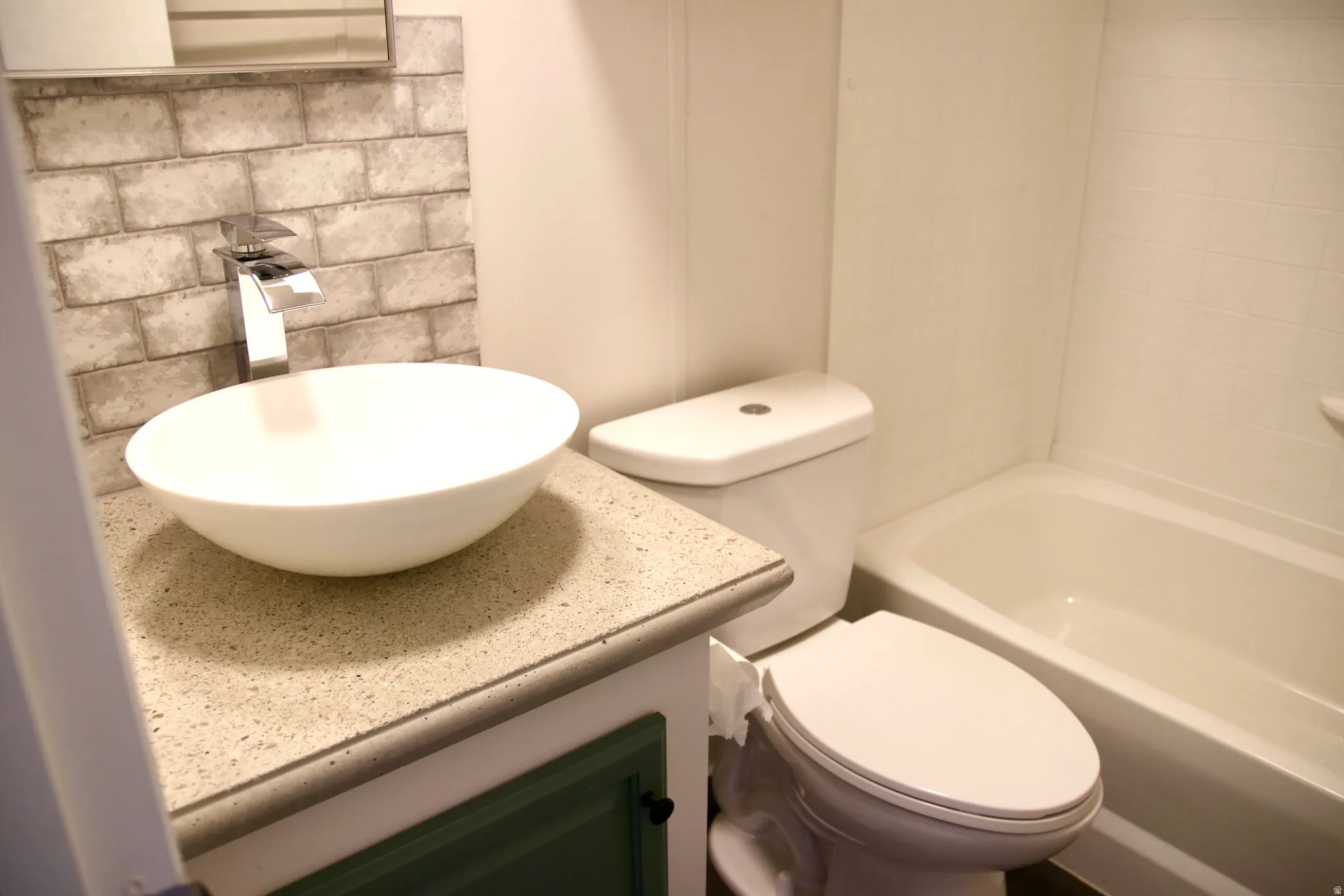 Guest bathroom featuring Vessel sink with a chrome waterfall faucet, brick-patterned tile backsplash, and a contemporary toilet