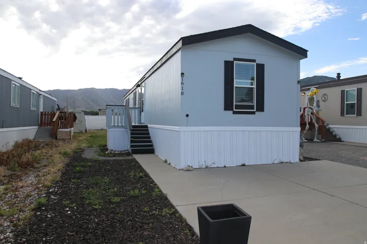 Single-level manufactured home featuring light gray  siding with new white skirting and new roof