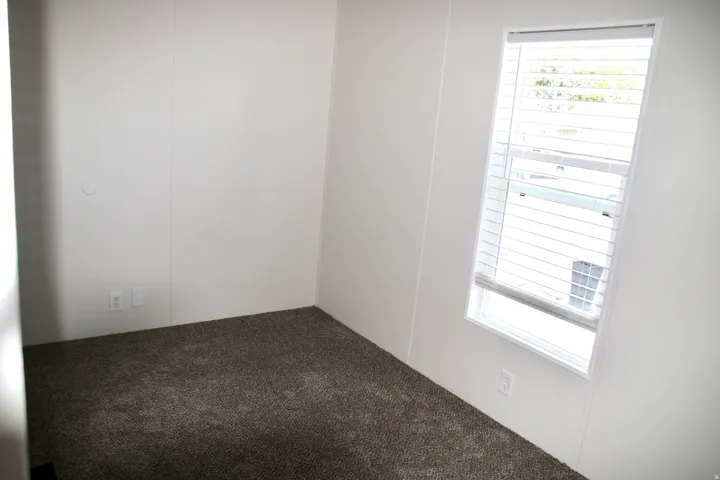 2nd bedroom featuring Carpeted room with white panel walls and a single window with blinds