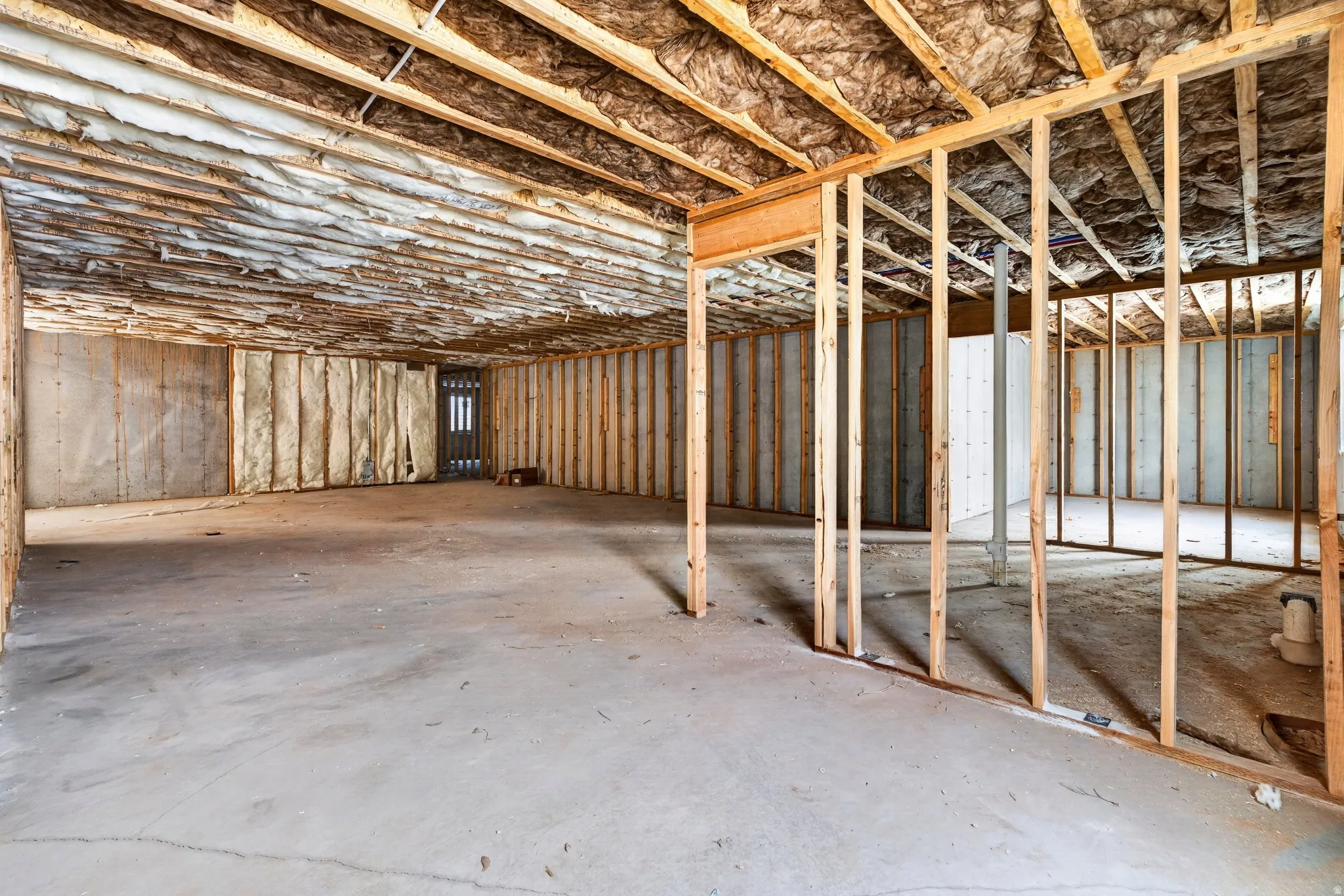 Unfinished basement featuring exposed framing, concrete flooring, and insulated walls