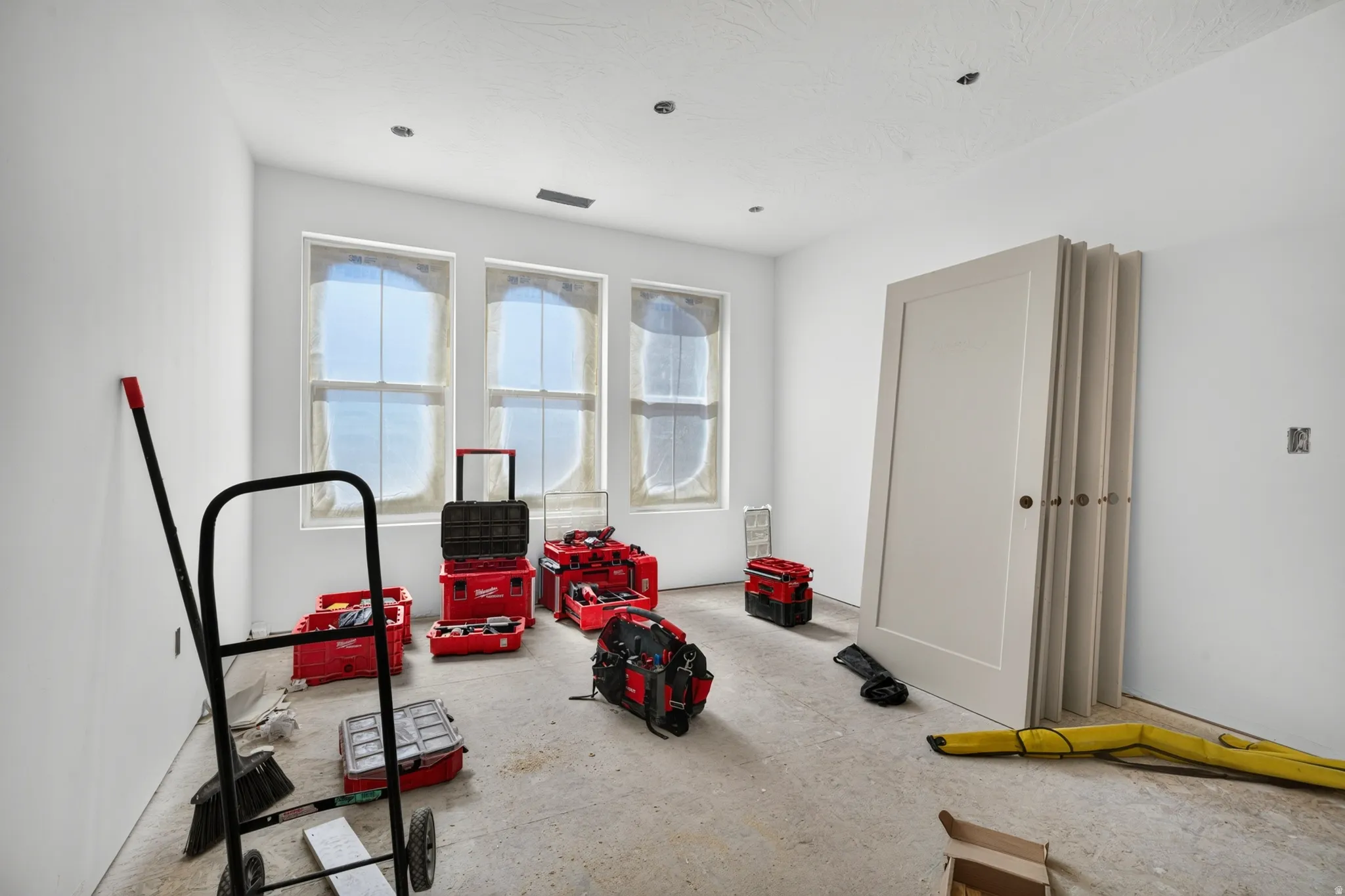 Recessed ceiling lighting, three double-hung windows, and a stack of paneled doors