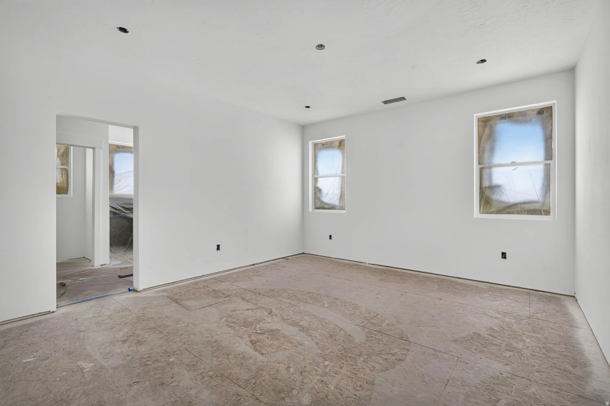 Spacious room featuring white painted walls, recessed ceiling lighting, and multiple windows
