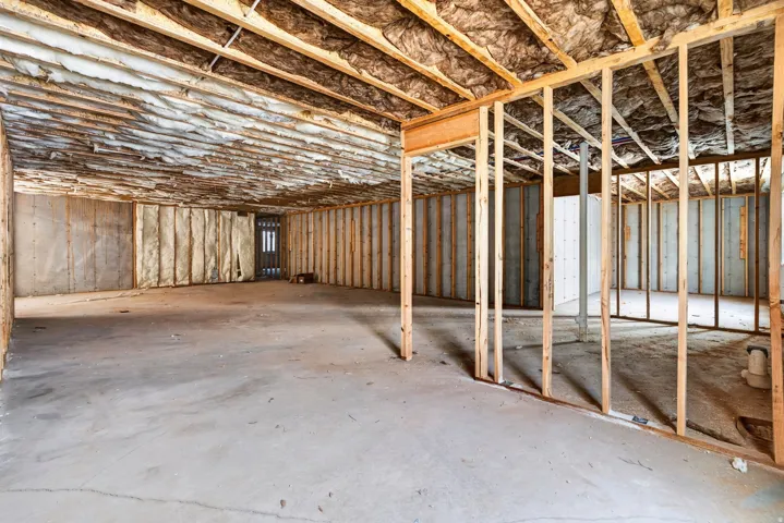 Unfinished basement featuring exposed framing, concrete flooring, and insulated walls