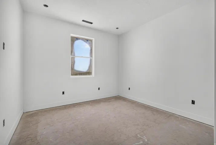 Recessed ceiling lighting with a single window and white trim, featuring unfinished flooring and white walls