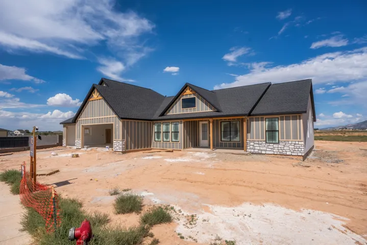 Board and batten siding, stone facade accents, dark shingle roofing, exposed timber architectural details, and an attached garage