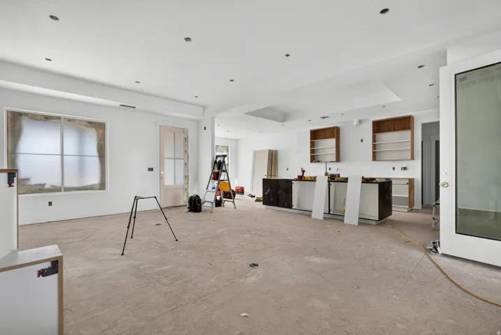 Recessed lighting throughout, tray ceiling detail, large window with ample natural light, built-in cabinetry, and a partial kitchen island