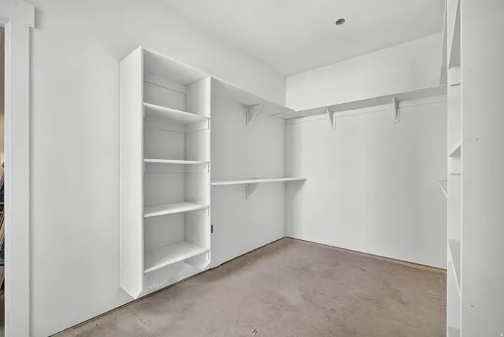 Built-in shelving, multiple hanging rods, and an overhead light fixture