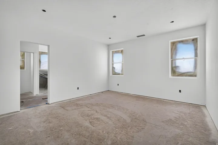 Spacious room featuring white painted walls, recessed ceiling lighting, and multiple windows