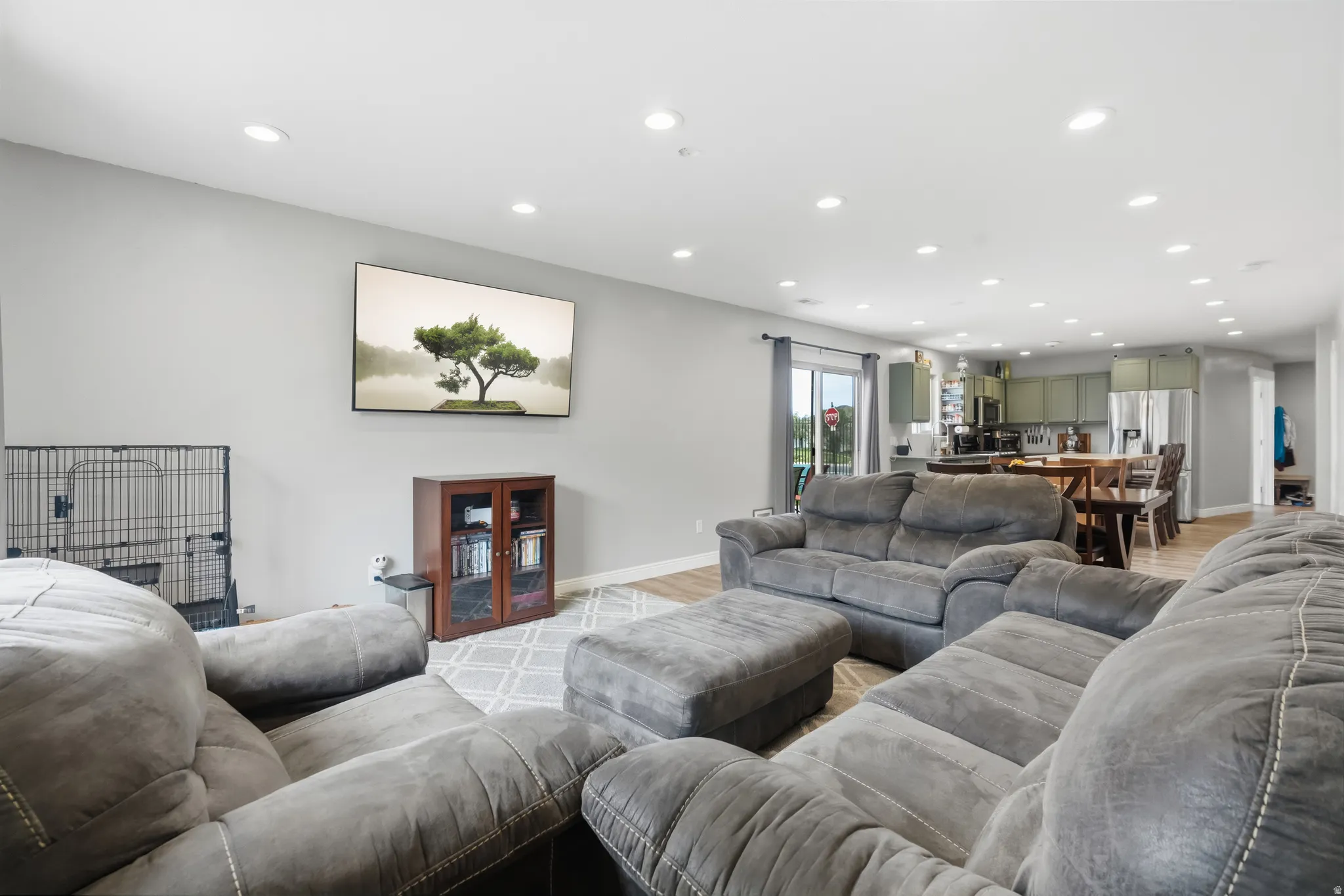 Open-concept living area featuring light gray walls, recessed lighting, and wood-finish flooring