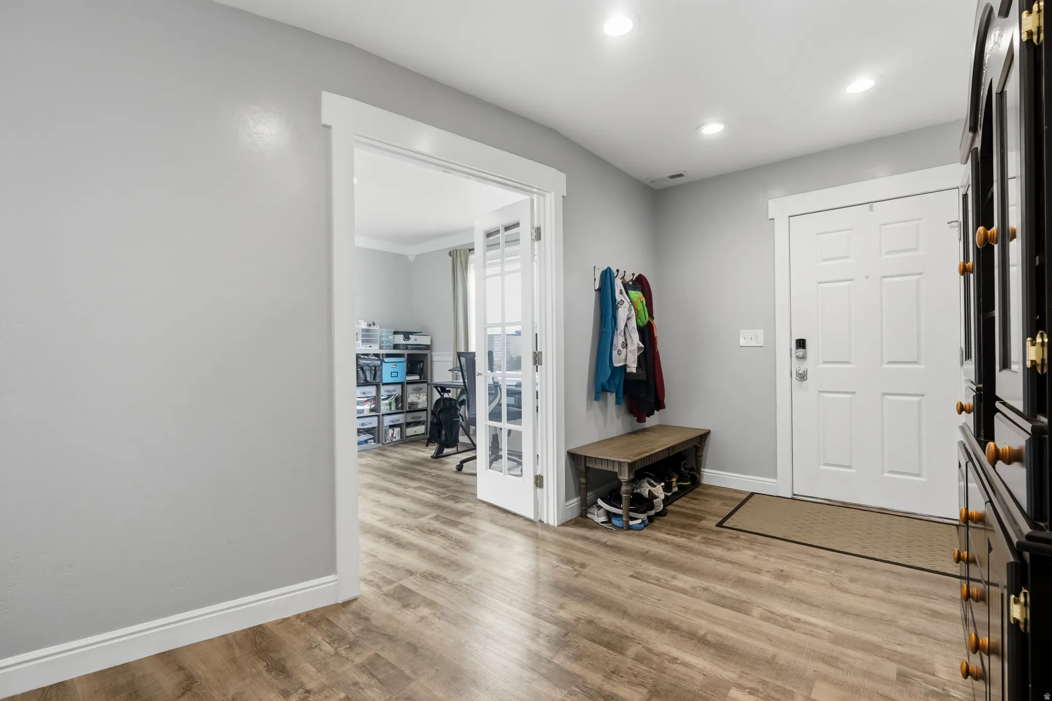 Entryway featuring wood-finish flooring, recessed lighting, a white panel door, and a dedicated room with French doors