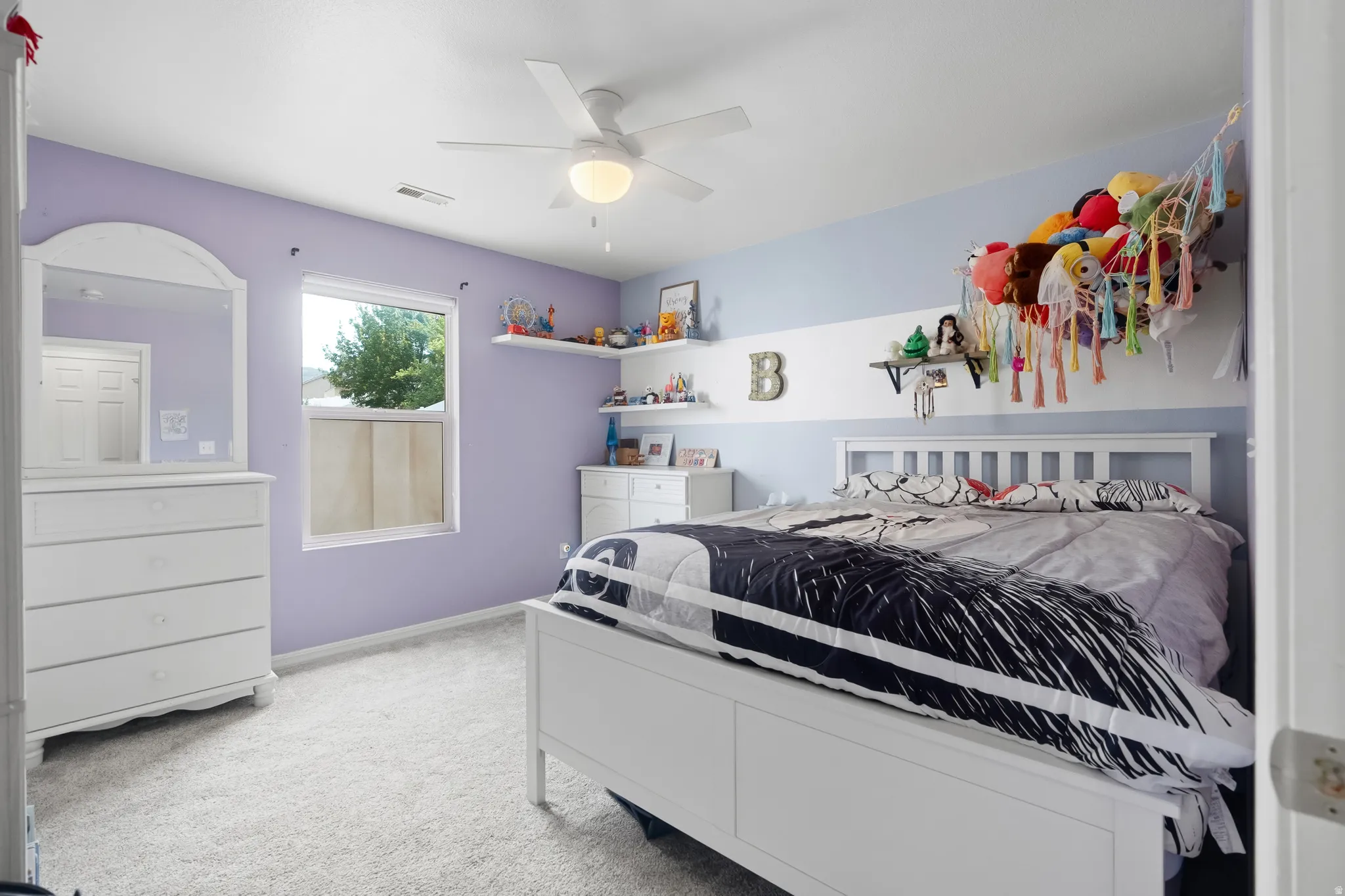 Carpeted room featuring a ceiling fan with integrated lighting, a window with exterior views, and built-in wall shelving