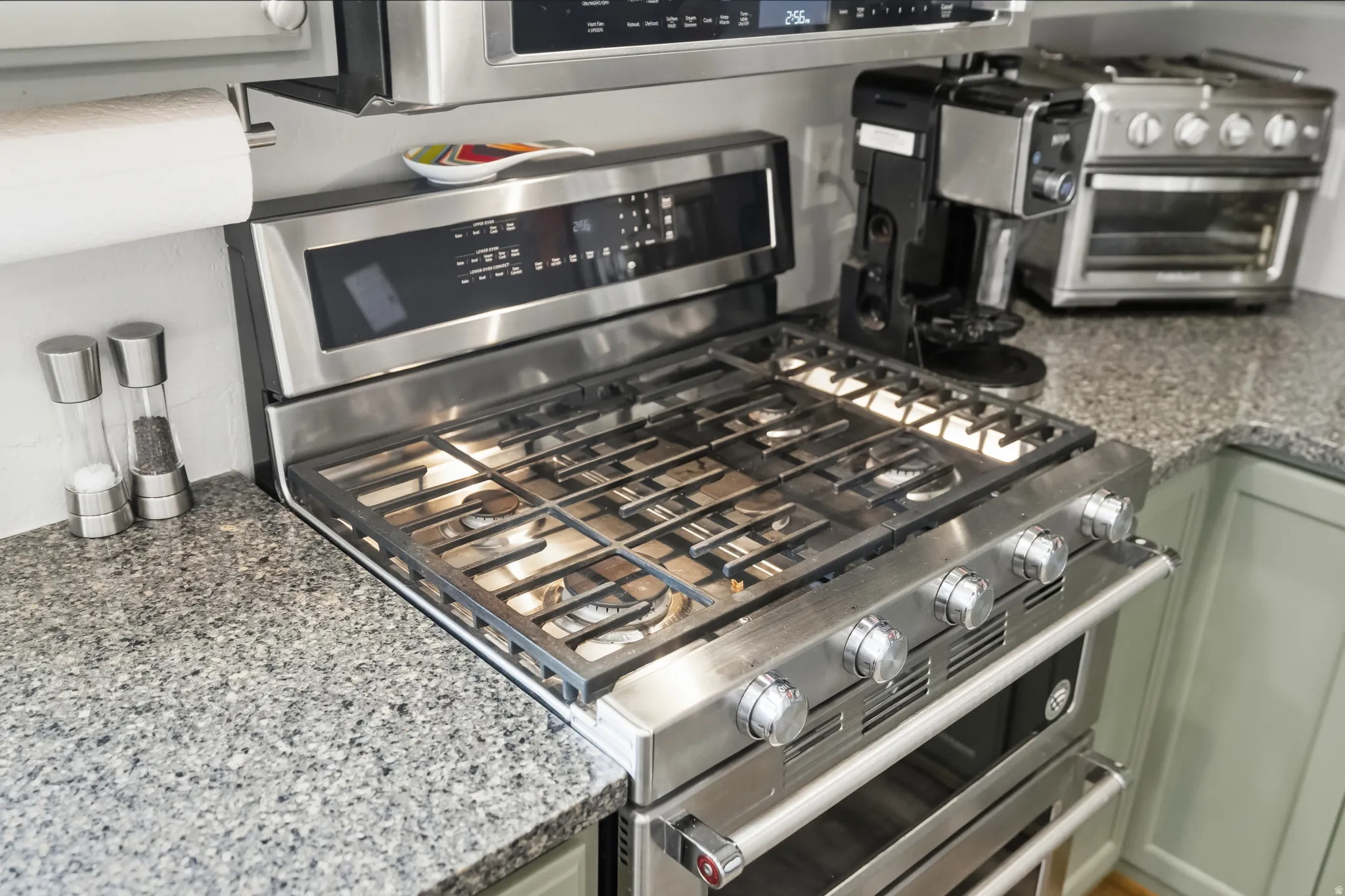 Stainless steel range with gas cooktop and integrated oven, set into a speckled granite countertop
