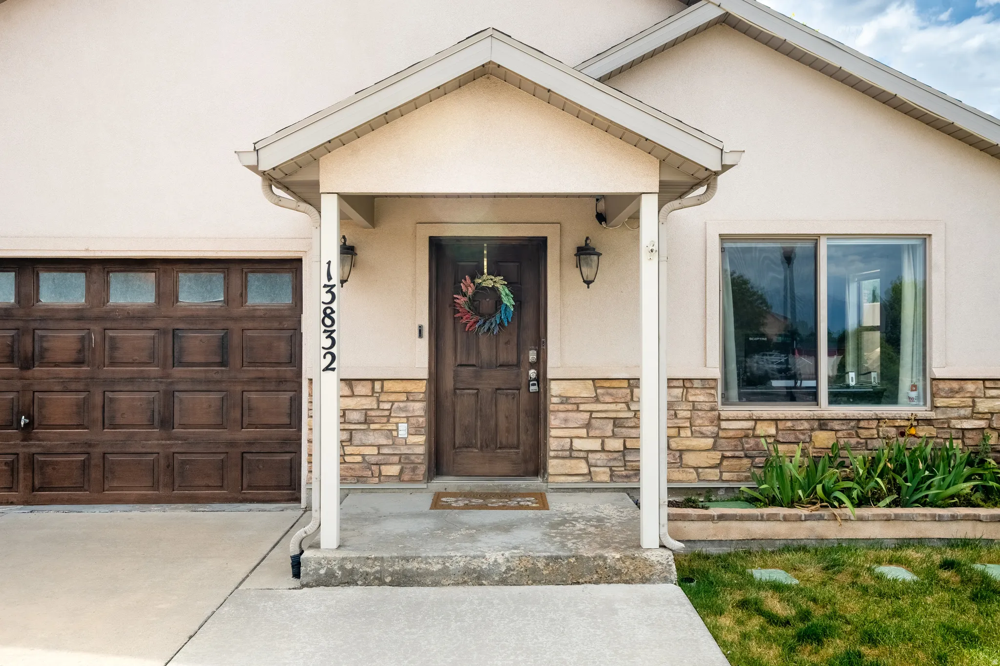 Exterior facade featuring a covered entry, stone accents, and a wood-finish garage door