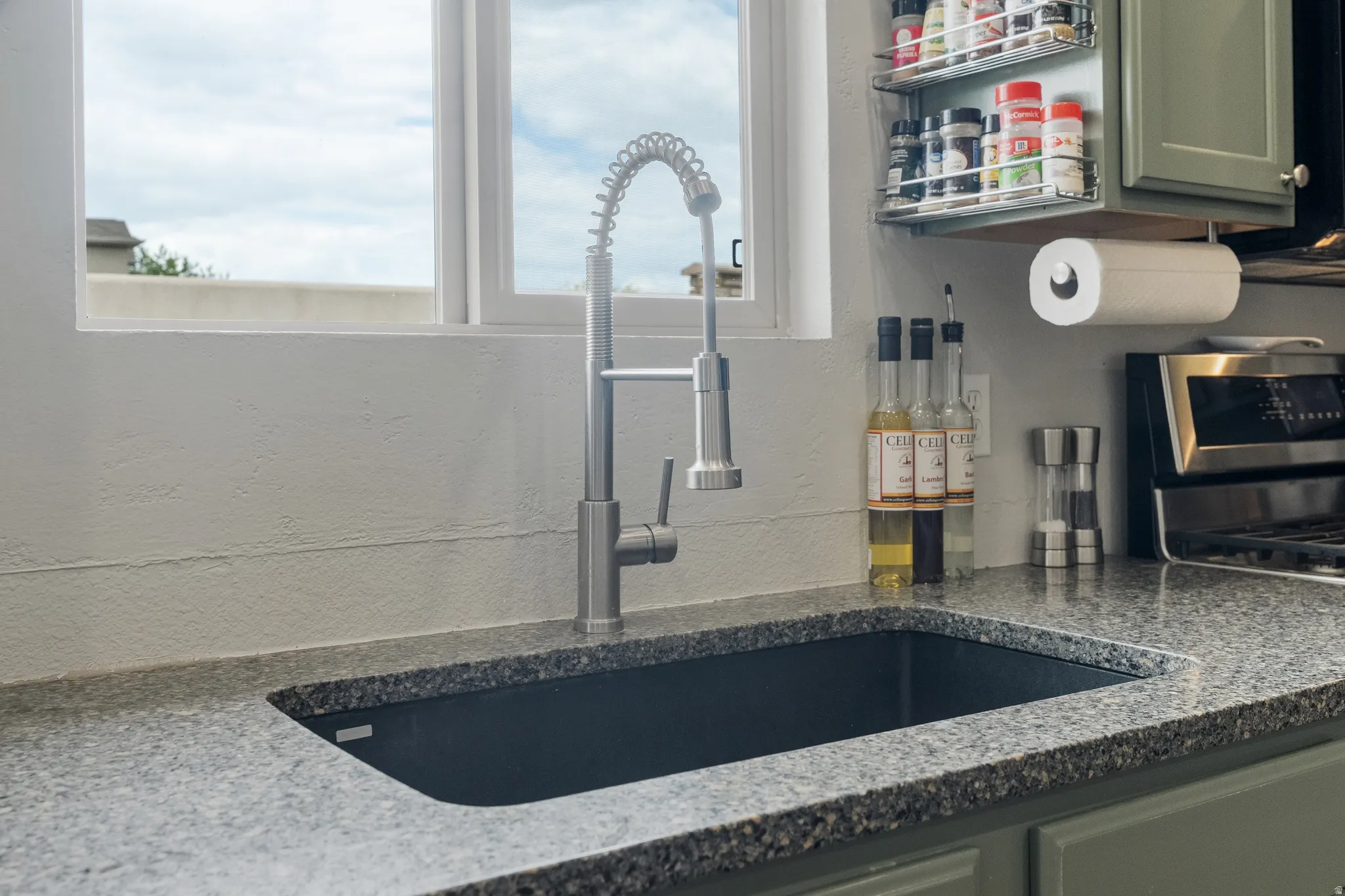 Kitchen workstation featuring a deep undermount sink, a high-arc pull-down faucet, and speckled countertops