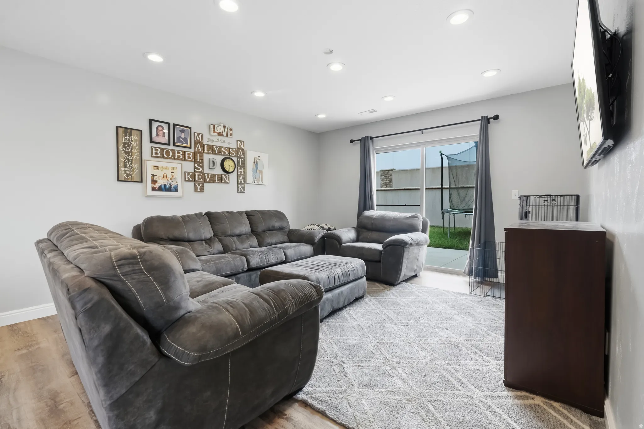 Spacious living area featuring wood-finish flooring, recessed lighting, and direct access to an outdoor patio through sliding glass doors