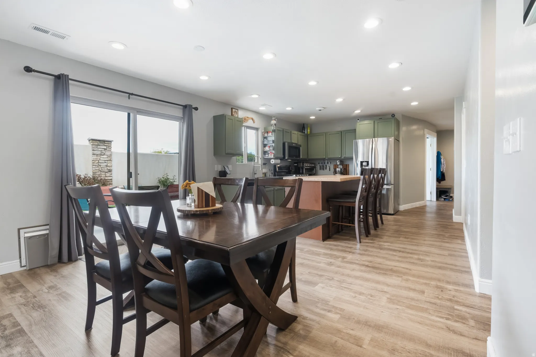 Open-concept living space featuring wood-finish flooring, recessed lighting, and a sliding glass door leading to an outdoor patio