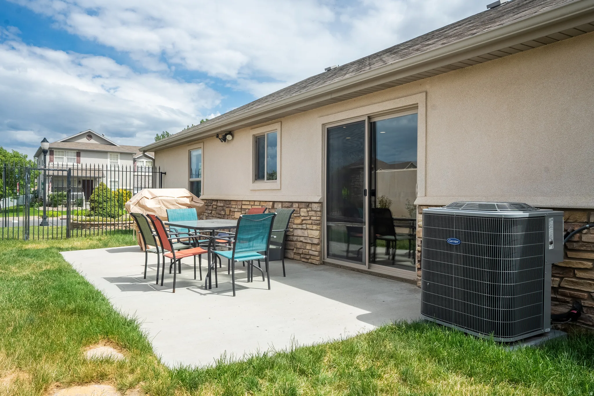 Poured concrete patio featuring stacked stone siding accents and a sliding glass door