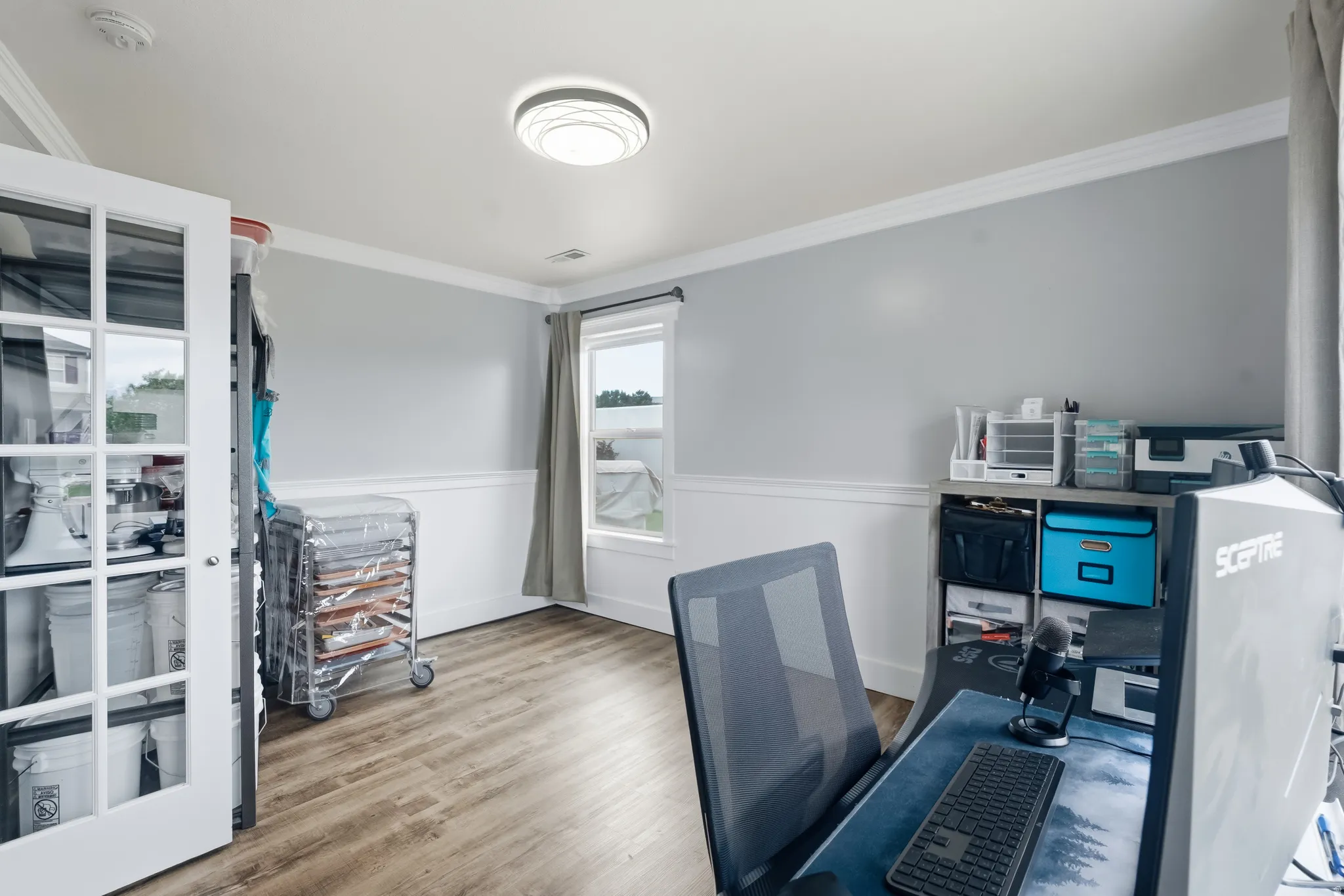 Interior room featuring wood-finish flooring, white wainscoting, and light gray walls