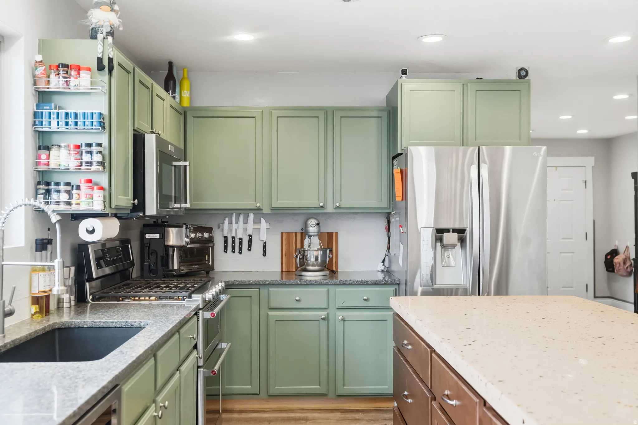 Kitchen featuring sage green cabinetry, a stainless steel gas range, a stainless steel French door refrigerator, recessed lighting, and a kitchen island with a light-toned countertop