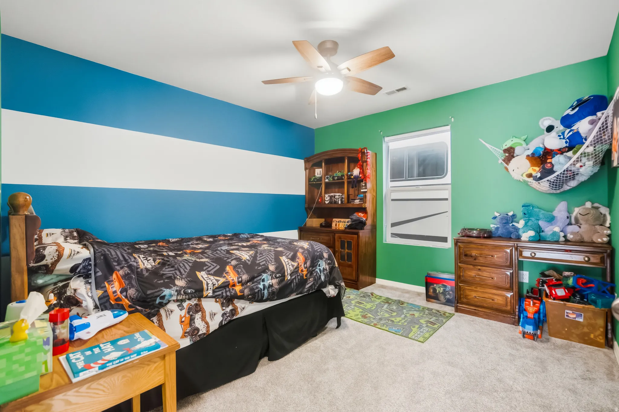 Carpeted room with a ceiling fan light fixture, window, and two-tone wall finishes
