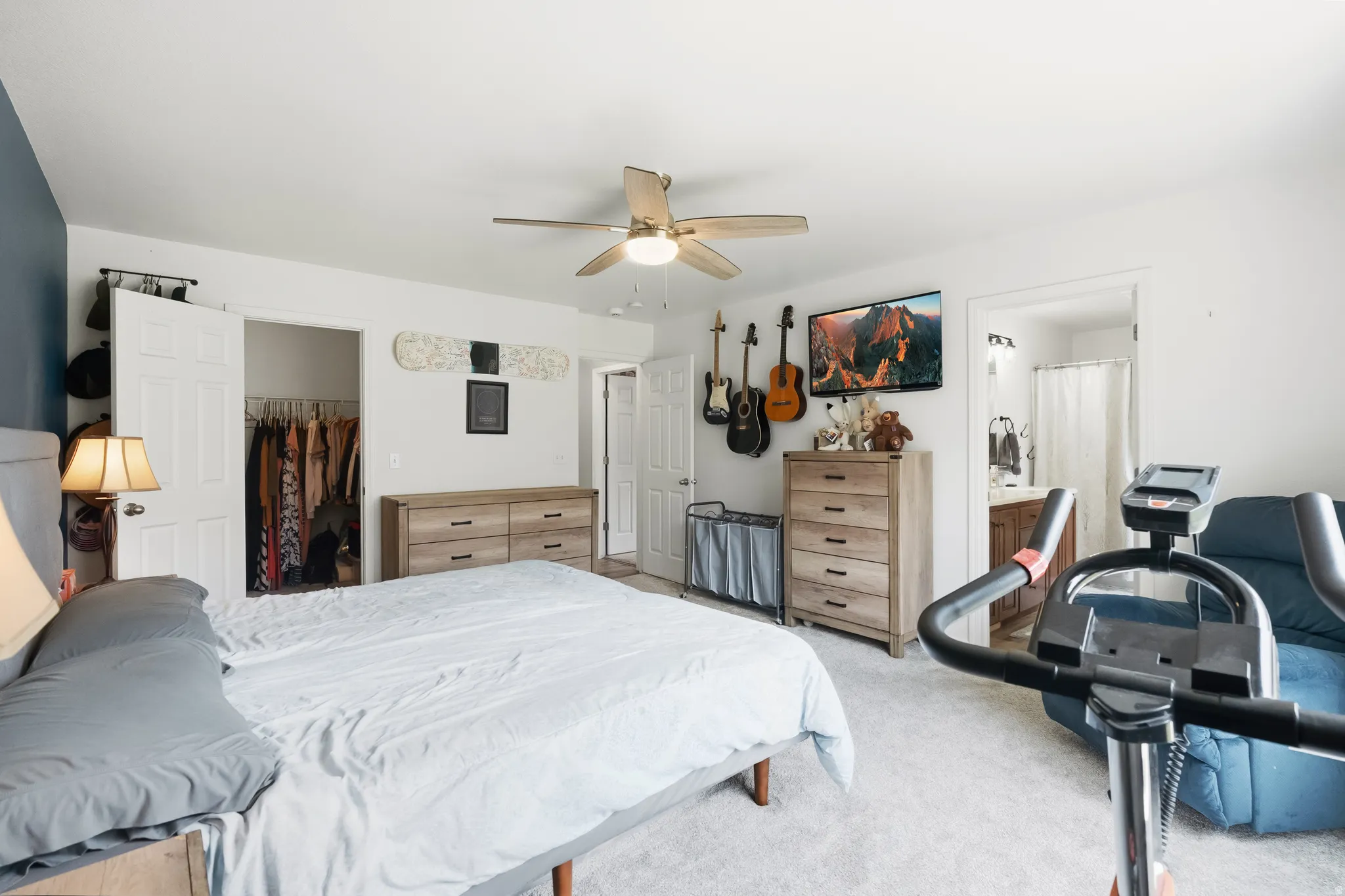 Spacious carpeted room featuring a ceiling fan, a built-in closet with double doors, and a partial view of an attached bathroom