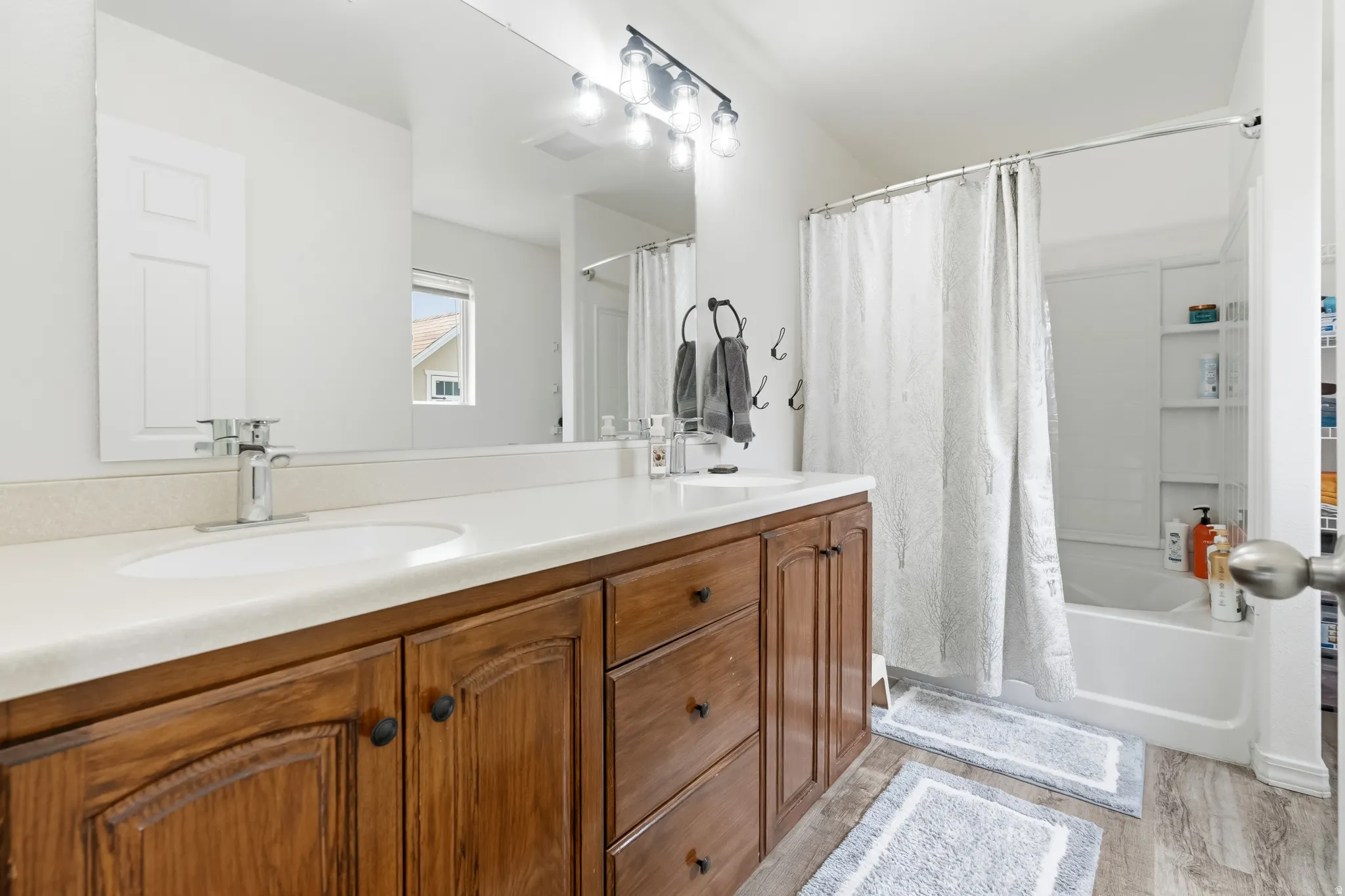 Bathroom featuring a dual vanity with wood-finish cabinetry and a light-toned countertop
