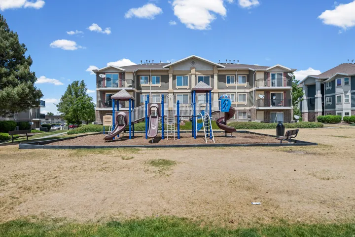 Community playground structure with slides and climbing elements, surrounded by a wood chip surface