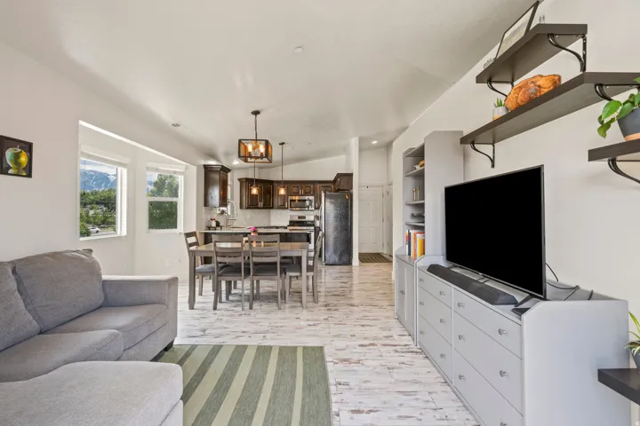 Open-concept living space featuring wood-finish flooring, a kitchen with dark wood cabinetry and stainless steel appliances, and built-in shelving
