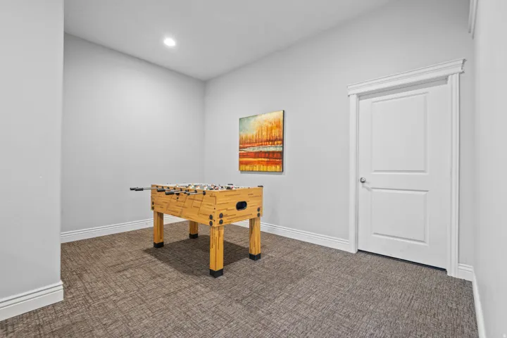 Carpeted room featuring a single recessed light, white baseboards, and a paneled interior door with decorative trim