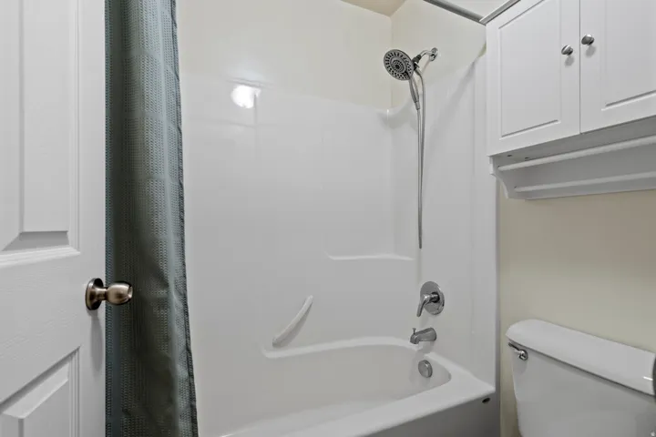 Bathtub/shower combination featuring a multi-function showerhead with handheld sprayer, integrated grab bar, and chrome fixtures