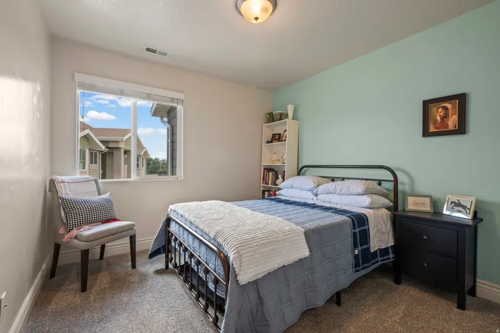 Carpeted bedroom featuring a large window, a built-in ceiling light fixture, and a built-in shelving unit
