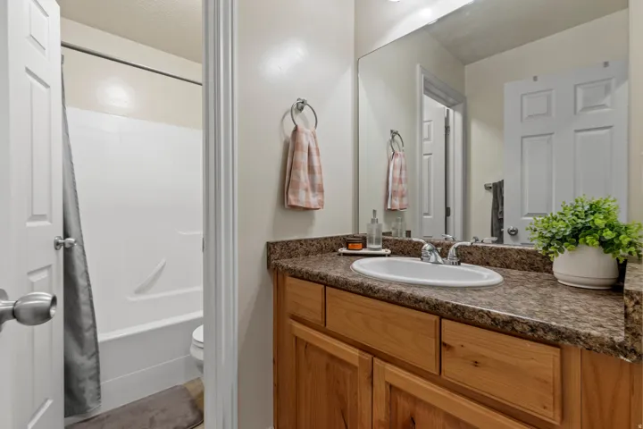 Bathroom featuring a wood-finish vanity with an integrated sink, a speckled countertop, and a large wall-mounted mirror