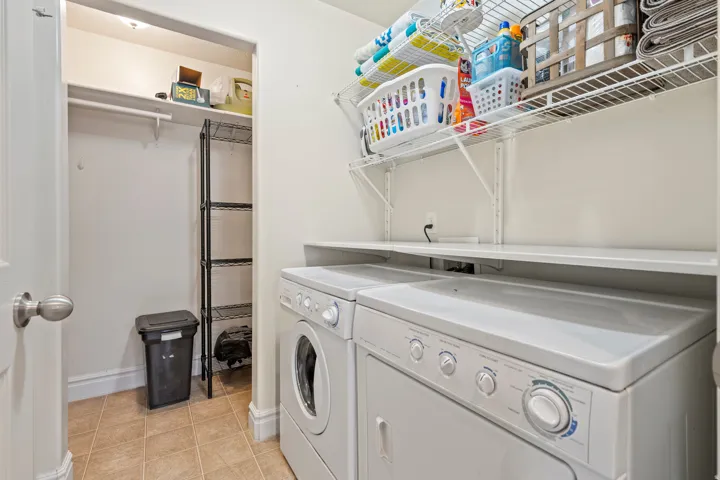 Dedicated laundry area featuring a washer and dryer, tile flooring, and a built-in shelf for organization