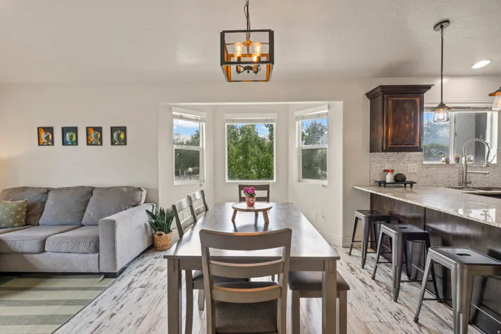 Open-concept living space featuring wood-finish flooring, a bay window, and a kitchen island with a granite-style countertop