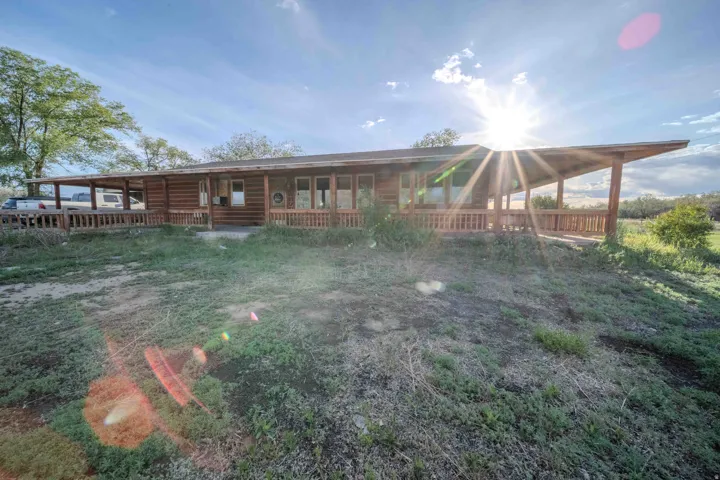 Log-style siding exterior with an expansive wrap-around porch featuring a wooden railing