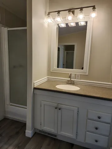 Bathroom vanity featuring a light-toned countertop with an integrated sink, dual cabinet storage, and a three-drawer stack