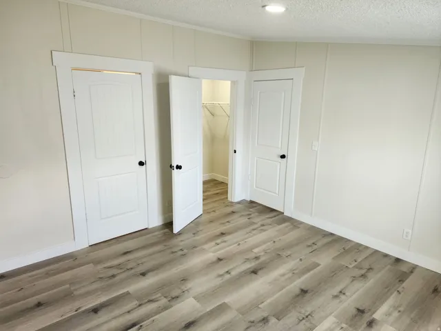 Interior room featuring light wood-finish flooring, white paneled walls, and crisp white trim