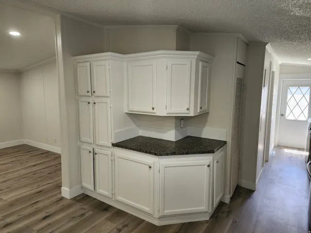 Corner built-in cabinetry with a dark speckled countertop, featuring upper and lower storage