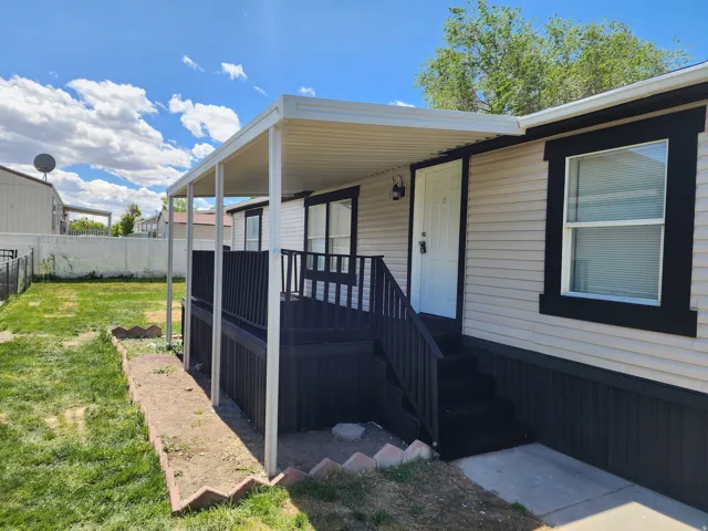 Covered porch entrance featuring dark railings and steps