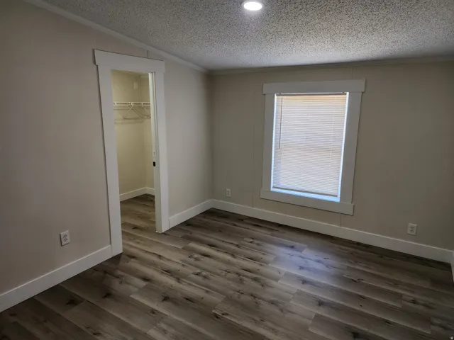 Room featuring wood-finish flooring, neutral wall tones, and white trim