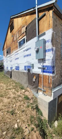 Exterior wall with exposed wood sheathing and partial weather-resistant barrier
