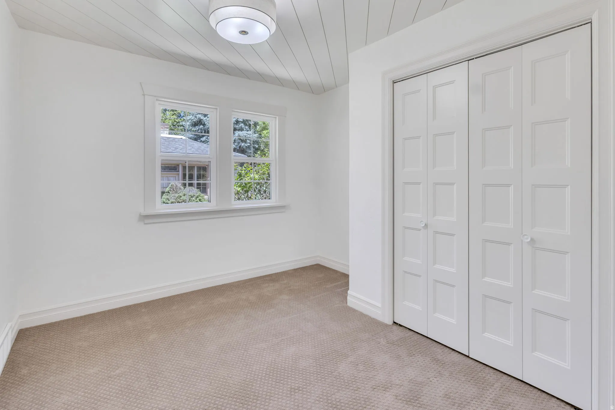 Carpeted room featuring white walls, a white shiplap ceiling, and a flush mount light fixture