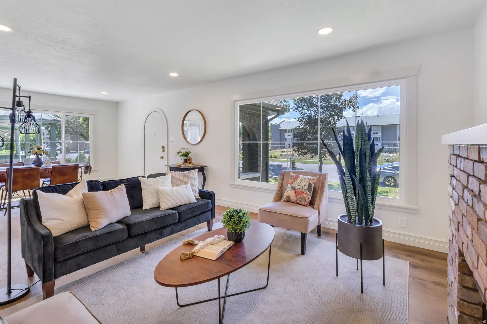 Bright living space featuring wood-finish flooring, recessed lighting, and a large picture window with white trim