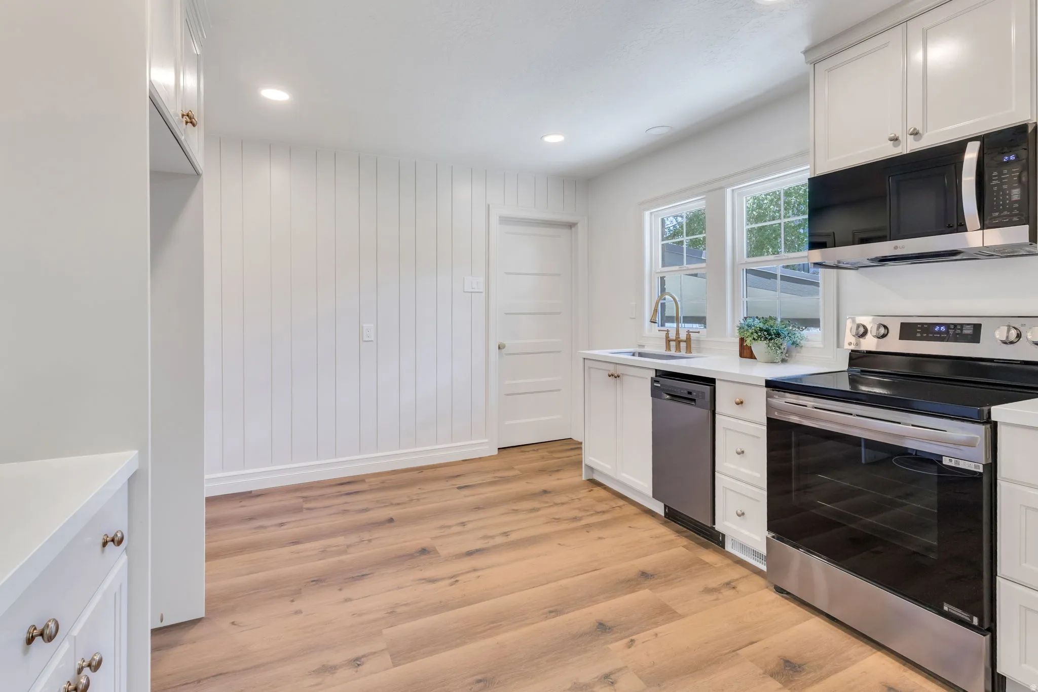 Kitchen featuring white cabinetry, light wood-finish flooring, recessed lighting, and stainless steel appliances including a range, microwave, and dishwasher